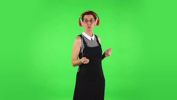 Funny Girl in Round Glasses Is Dancing and Enjoying Music in Big Red Headphones, Green Screen