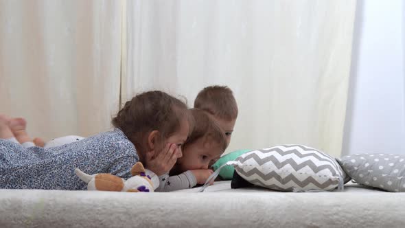 Smiling Preschool Toddler Children In Pajamas Watching Cartoon on Smartphone on Bed