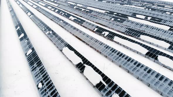 AERIAL: Photovoltaic in Winter Covered with Snow. Solar Panels Among the Snow Drifts, Covered with