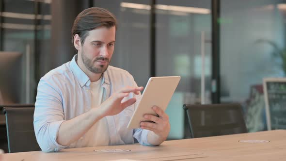 Attractive Mature Adult Man Using Tablet in Office