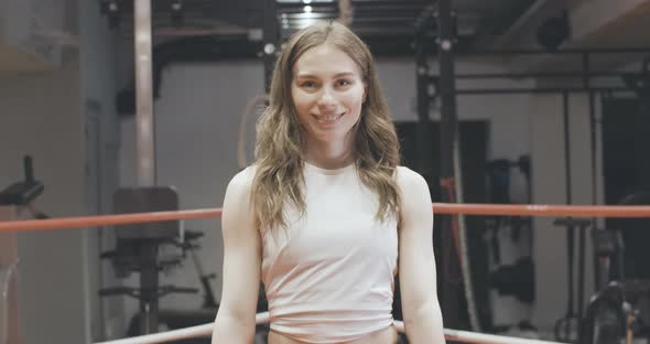 Happy Female Boxer Posing on Boxing Ring. Portrait of Smiling Brunette Caucasian Woman Punching alt