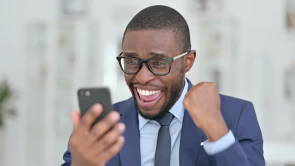 Portrait of African Businessman Celebrating Success on Smartphone 