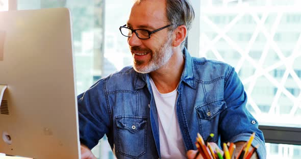 Happy male graphic designer using graphic tablet at desk