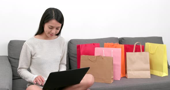 Shopping woman use of notebook computer with lots shopping bag at home