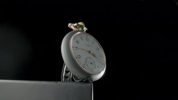 Silver Antique Pocket Watch on a Stand Rotating on a Black Isolated Background