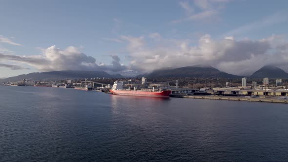 Drone flying towards cargo ship in Vancouver commercial port, Canada. Aerial forward