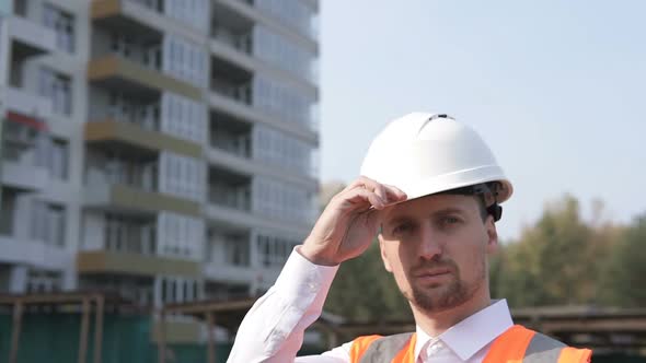 Construction Engineer Puts on a Helmet at a Construction Site