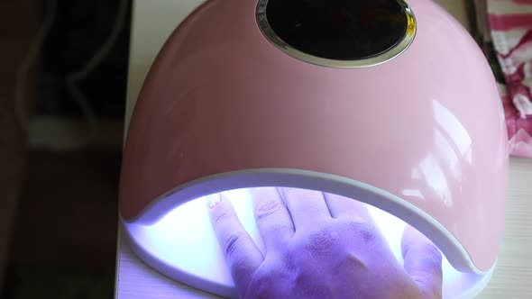 A Woman Dries Her Nails In An Ultraviolet Lamp. She Gives Herself A Manicure.