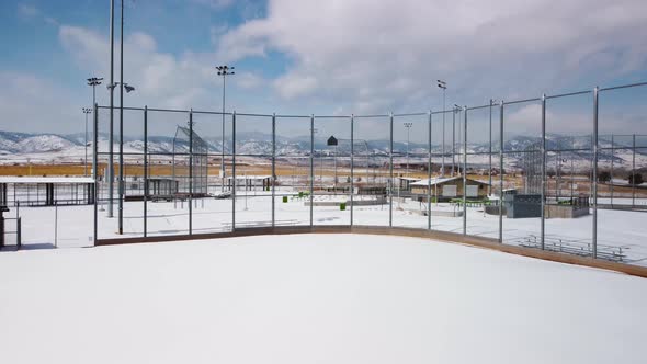 Reveal of baseball and softball field during the winter with fresh snow in front of the Colorado Roc