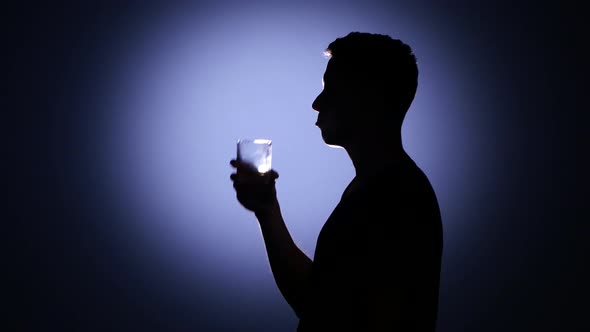 Alcohol Addiction. Man Drinking Whiskey. Back Light