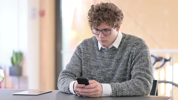 Young Man Using Smartphone at Work 