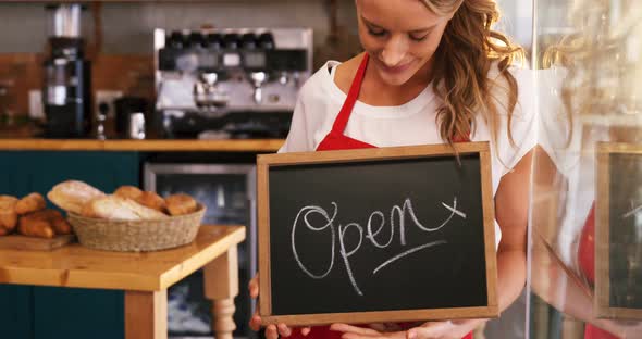 Smiling waitress holding a open sign board