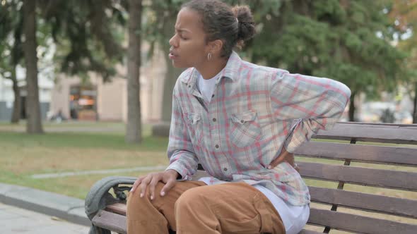 African Woman Having Back Pain While Sitting on Bench Outdoor