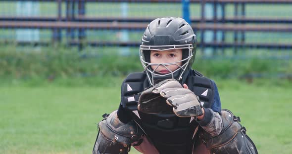 Portrait of a Boy Baseball Player on a Blurry Background, the Catcher in Protective Gear Catches a