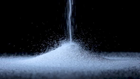 Particles of White Dry Sand are Pouring Down Forming a Hill on an Isolated Black Background with