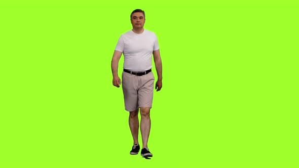 Adult Man in Shorts and White T-shirt Walks on Green Background