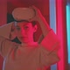 Young woman holding vr goggles in hand in red neon light looking into the camera - VideoHive Item for Sale