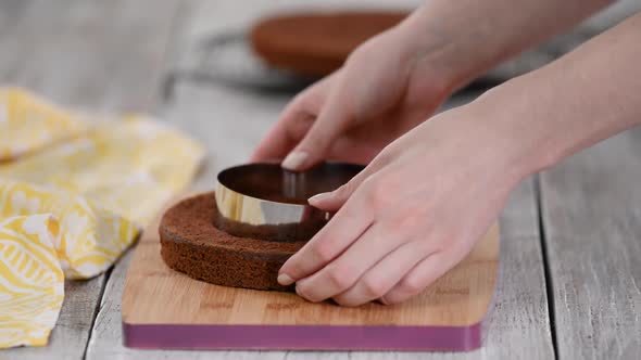 Female Hands Cutting the Sponge Cake with a Confectionery Ring