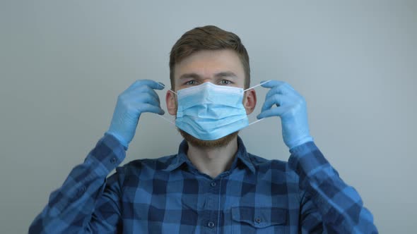 Young man in latex loves putting on protective medical mask for pandemic protection of virus