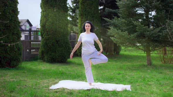 The Girl is Doing Yoga in the Garden