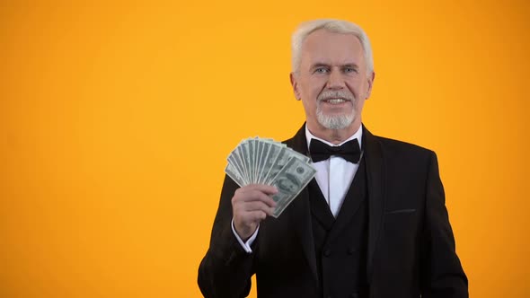 Cheerful Senior Male With Dollars Showing Hey You Gesture, Successful Investment