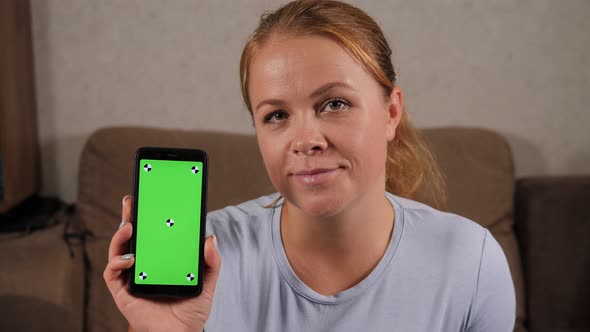 Portrait of a Woman at Home She is Holding a Phone with a Green Screen