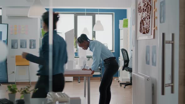 Woman Architect Working on Blueprints Plan to Design Construction Layout with Building Model