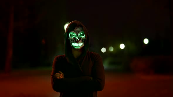 Ghost on Street in Night Person with Glowing Skull Mask and Hood on Head