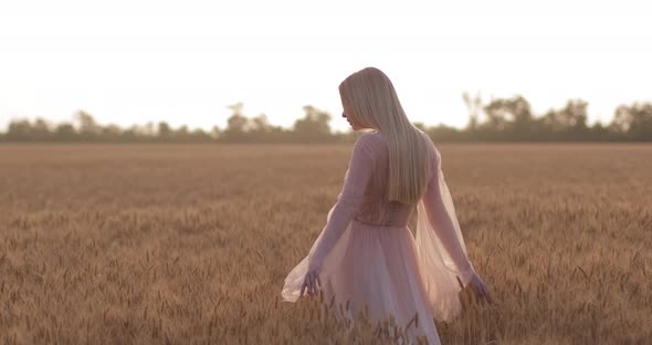 A young girl in wedding dress walking in slow motion through a field and hands 