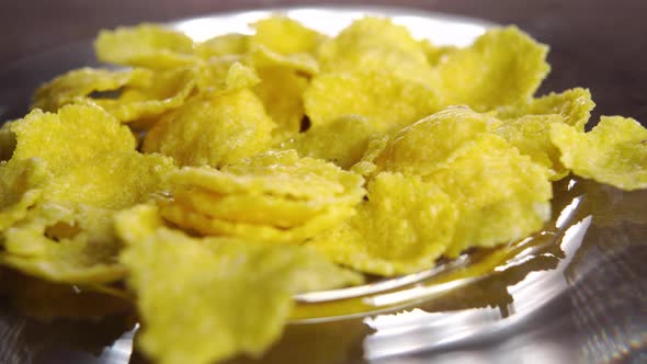 Dry cornflakes product on a shiny bowl. Macro. Rotation. Corn breakfast snack