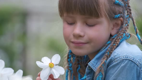 Happy Child Girl Playing in Summer Garden Enjoying Sweet Scent of White Narcissus Flowers on Sunny