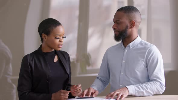 African Woman at Negotiating Meeting in Office with Afro Male Financial Consultant Real Estate Agent