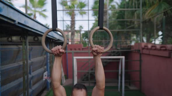 Strong Man Performing Pull Ups on Gymnastic Rings