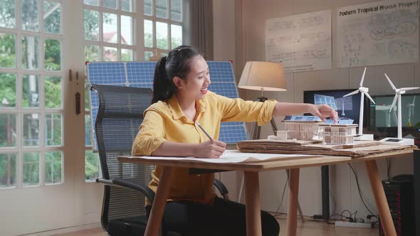 Woman Sketch On The Blueprint and Putting Solar On The Roof Of Model Small House