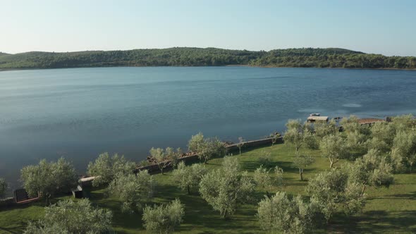 Aerial wide shot of a beautiful landscape in Croatia. Garden and lagoon in the foreground, small hil