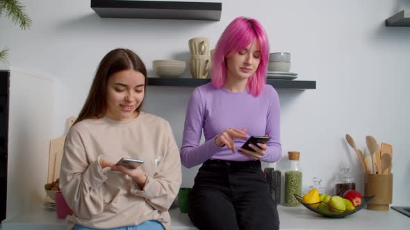 Cute Woman with Birth Anomaly and Girlfriend Networking on Cellphones in Kitchen