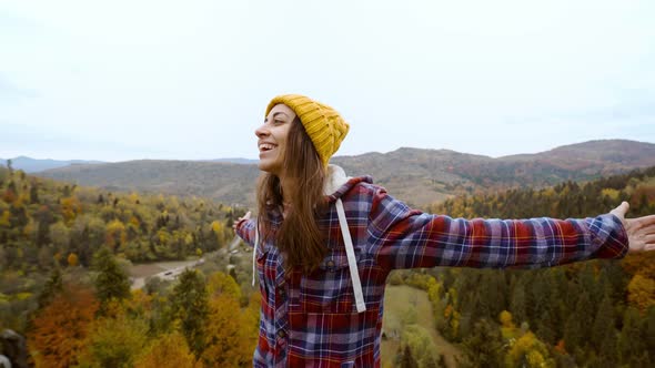 POV First Person View of Woman Hiker in Warm Casual Wear Sits on Edge of Cliff Against Background of