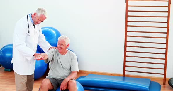 Smiling Doctor Helping Patient Move his Arm and Shoulder