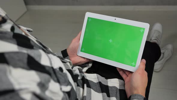 Man Sitting on Chair Looking at Digital Tablet with Green Screen Chroma Key