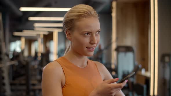 Romantic Sportswoman Texting Message in Sport Club. Athlete Girl Standing at Gym
