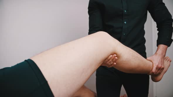 Young Man Having His Knee Examined. Physiotherapy Knee Flexibility