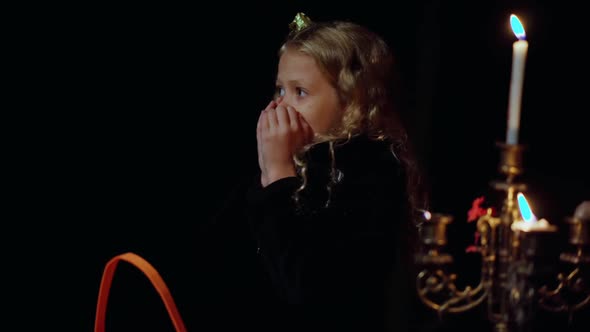 Portrait of Scared Charming Little Girl in Dark Forest on Halloween Night with Lightnings Flashing