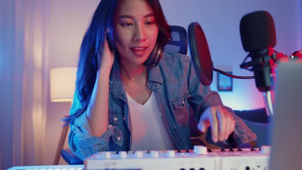 Happy asia girl blogger play synthesizer keyboard wear headphone and record music with sound mixer.
