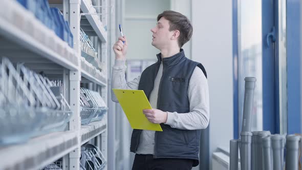 Professional Worker Looking at Goods on Shelves Filling in Register and Looking at Camera Smiling