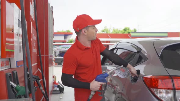 A Caucasian man, people, worker filling up fuel by using petrol pump at gasoline petrol station