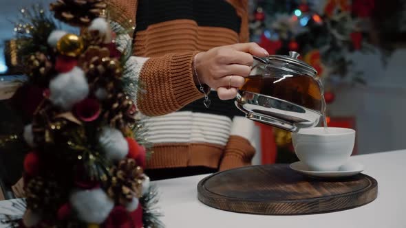 Close Up of Woman Pouring Cup of Tea From Kettle at Home