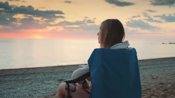 Woman Drinking From Thermos and Sitting on Camping Chairs on the Beach