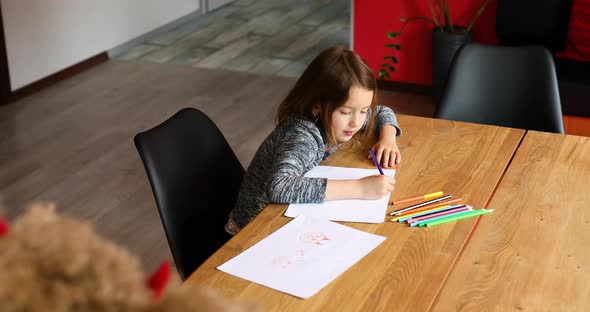 School girl drawing and writing a picture with crayons, using colored pencils