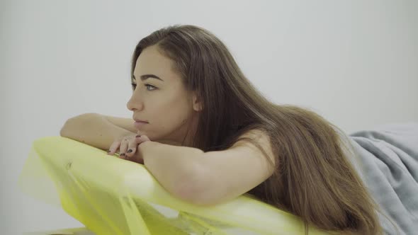 Girl Lying on a Couch During Treatment in Salon Turning at Camera and Smiling