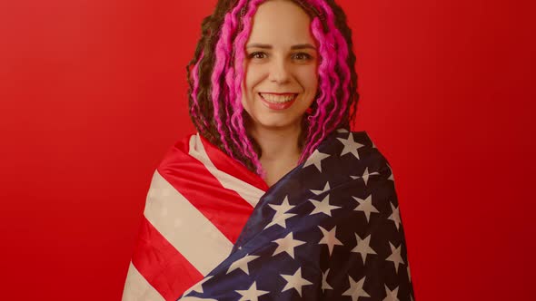 Young Woman Wrapped in American Flag on Red Background